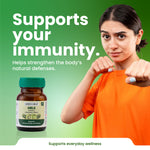 Person in orange shirt with a bottle of Green Milk Amla Capsules on a green background, promoting immunity support.
