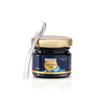 Jar of Shilajit resin with a spoon on a white background